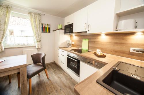 eine Küche mit einer Theke, einem Tisch und einem Waschbecken in der Unterkunft Frieslandstern - Ferienhof und Hotel in Wangerland
