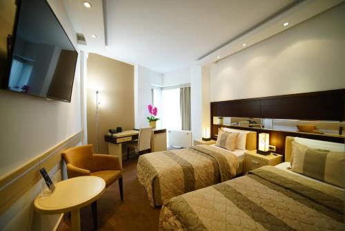 una camera d'albergo con 2 letti e una scrivania di Hotel Vojvodina a Zrenjanin