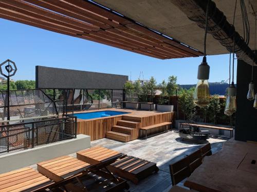 a patio with a swimming pool and wooden furniture at Lofts Mai Self Amenities in Tigre