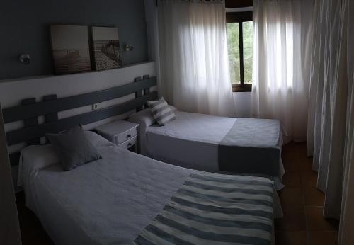 1 dormitorio con 2 camas y ventana en Viviendas Turísticas Vacacionales Allida en Playa Migjorn