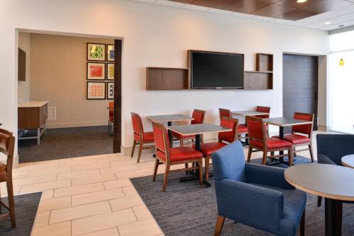 a waiting room with tables and chairs and a flat screen tv at Holiday Inn Express & Suites - Southgate - Detroit Area by IHG in Southgate