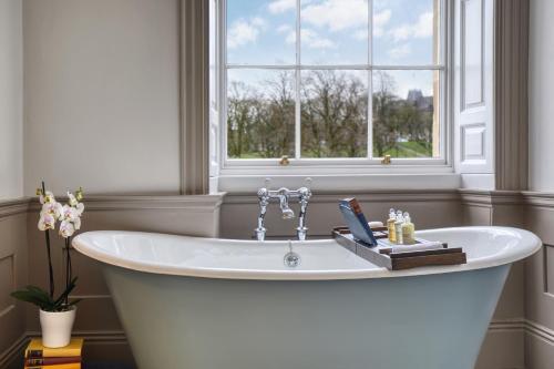 eine weiße Badewanne in einem Zimmer mit Fenster in der Unterkunft Ensana Buxton Crescent in Buxton