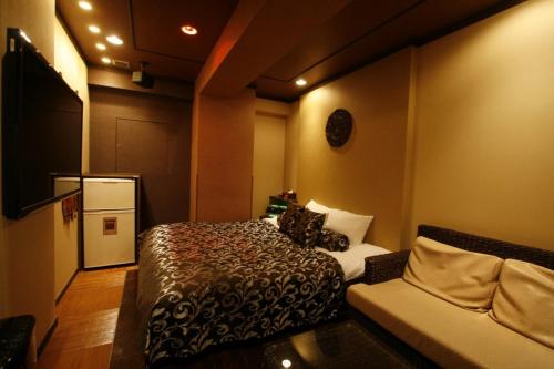 a small room with a bed and a couch at Hotel Pasion Resort (Adult Only) in Fukushima
