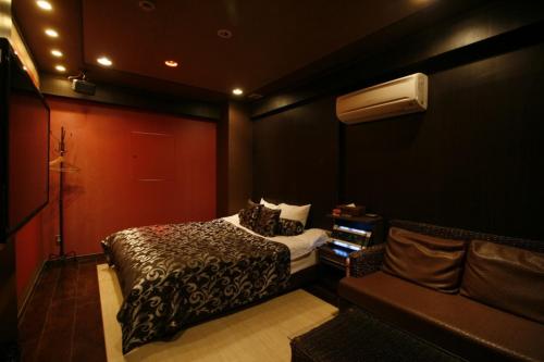 a bedroom with a bed and a couch in it at Hotel Pasion Resort (Adult Only) in Fukushima