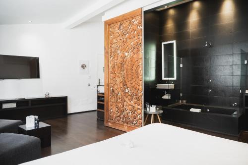 a bedroom with a large wooden door with a tub and a television at Puro Hotel Oasis Urbano in Palma de Mallorca