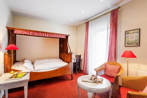 a bedroom with a canopy bed and a table and chairs at Romantik Hotel Hof zur Linde in Münster
