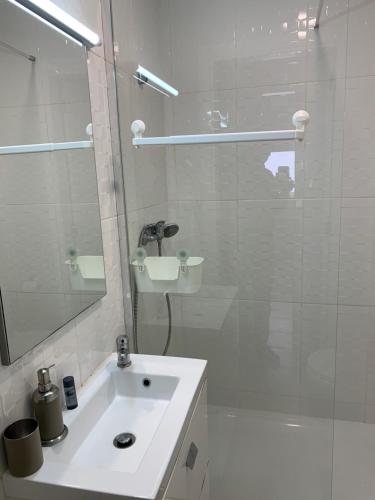 uma casa de banho branca com um lavatório e um chuveiro em TangoSierraResidences em Alcochete