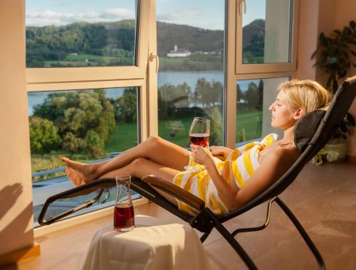a woman sitting in a chair with a glass of wine at Hotel Seehof in Sankt Georgen am Längsee