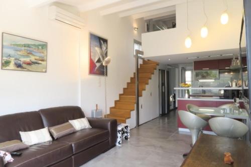 un salon avec un canapé marron et un escalier dans l'établissement Naturiste Cap d'Agde Villa Héliovillage 116, au Cap d'Agde