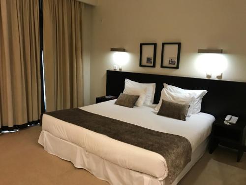 ein Hotelzimmer mit einem großen Bett mit zwei Kissen in der Unterkunft Hotel SJ in Tondela