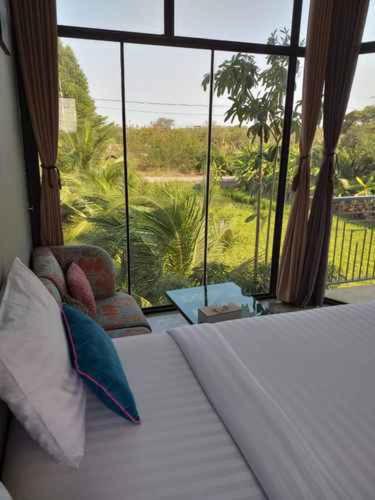 a bedroom with a bed and a large window at Plernsalaya resort in Salaya