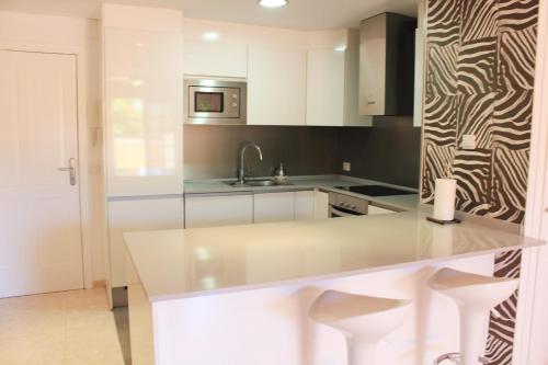 eine Küche mit weißen Schränken und einer Theke mit Stühlen in der Unterkunft Perfecto apartamento de playa in Callao Salvaje