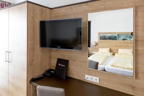 1 dormitorio con 1 cama y TV en la pared en Hotel-Restaurant Planaihof, en Schladming