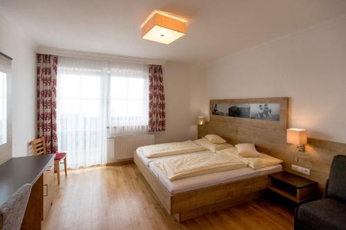 a bedroom with a bed and a desk and windows at Hotel-Restaurant Planaihof in Schladming