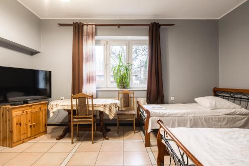 a room with two beds and a table and a television at Gościniec Exclusive in Warsaw