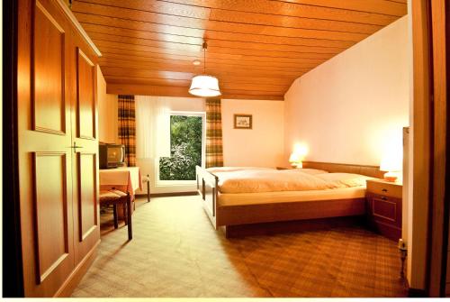 Schlafzimmer mit einem Bett, einem Schreibtisch und einem Fenster in der Unterkunft Hotel Schauenburg in Tholey