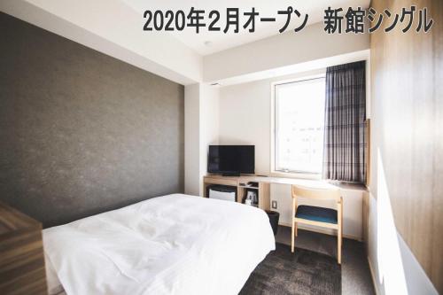 a bedroom with a bed and a desk and a television at Hotel Kajiwara in Matsuyama