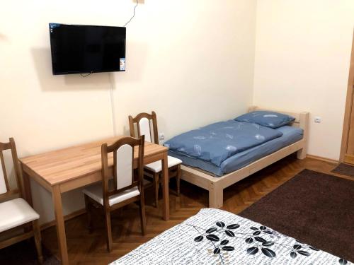 Kleines Zimmer mit einem Tisch, einem Bett und einem TV. in der Unterkunft GIL apartments, Korzo 7,2 centre in Uschhorod