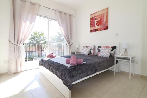 una camera da letto con un letto con cuscini rosa e una finestra di Cyking 2 bed Apartment with pool & 10 min to beach a Paphos