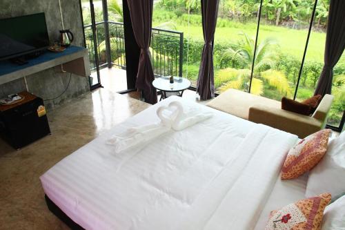 a bedroom with a white bed with a bow on it at Plernsalaya resort in Salaya