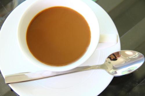 een kopje koffie op een bord met een lepel bij Plernsalaya resort in Salaya