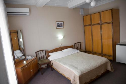 a bedroom with a bed and a dresser at Chisinau Hotel in Chişinău