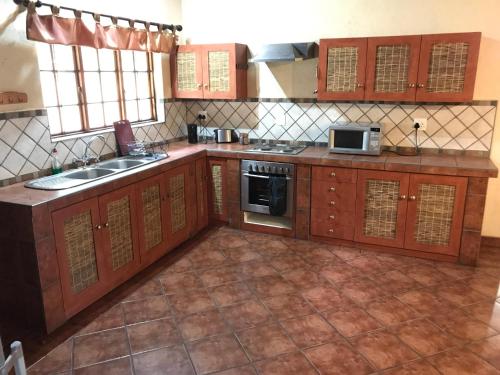 a kitchen with wooden cabinets and a sink and a microwave at Amafu Forest Lodge in Hoedspruit