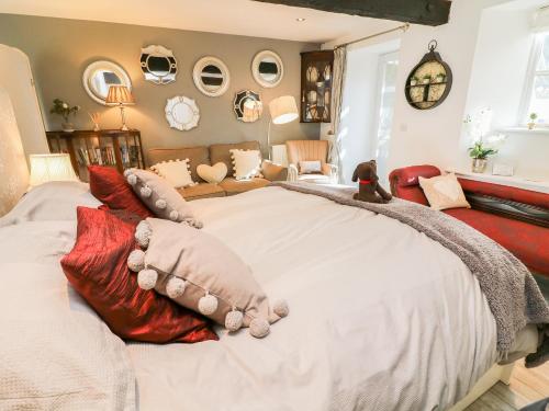 um quarto com uma grande cama branca com almofadas vermelhas em Blacksmith Cottage em Grassington