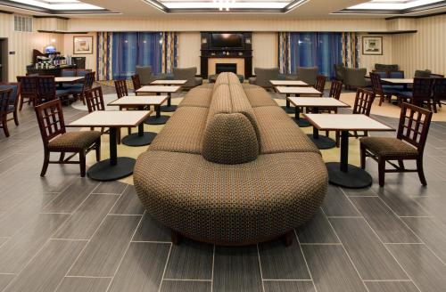 a cafeteria with tables and chairs and a couch at Holiday Inn Express & Suites Austin South-Buda by IHG in Buda