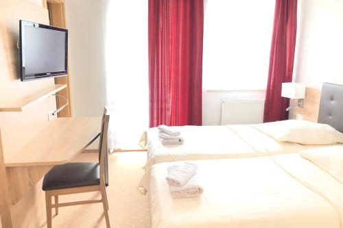Habitación de hotel con 2 camas, escritorio y TV. en Hotel & Restaurant Miranda en Siek