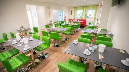 a dining room with green chairs and tables at Hotel Astoria in Karlsruhe