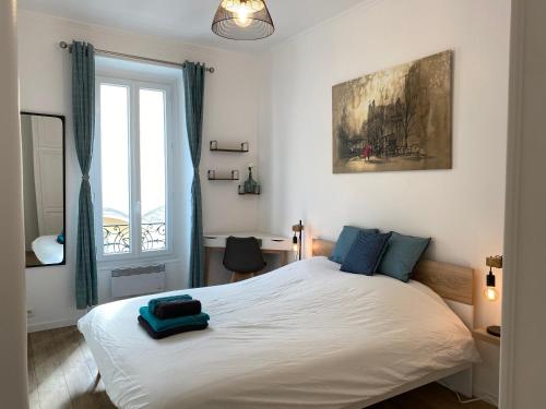 1 dormitorio con 1 cama blanca grande con almohadas azules en Chic and Cosy apartment close to the port and Garibaldi en Niza