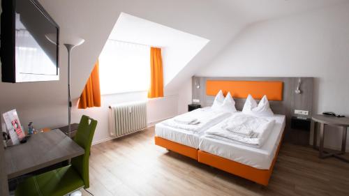 um quarto com uma cama laranja e branca e uma secretária. em Hotel Astoria em Karlsruhe