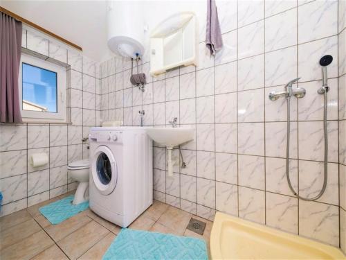 a bathroom with a washing machine and a toilet at Apartment Sensa in Trogir