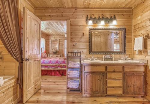 a log cabin bathroom with a sink and a mirror at Always and Forever-Hot Tub, Arcade, Near the Parkway! in Pigeon Forge