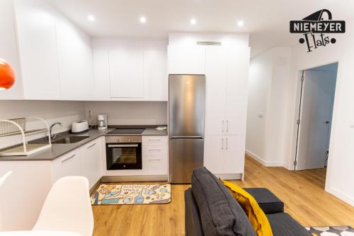 a kitchen with white cabinets and a stainless steel refrigerator at Niemeyer flats 1 piso VUT-1949-AS in Avilés