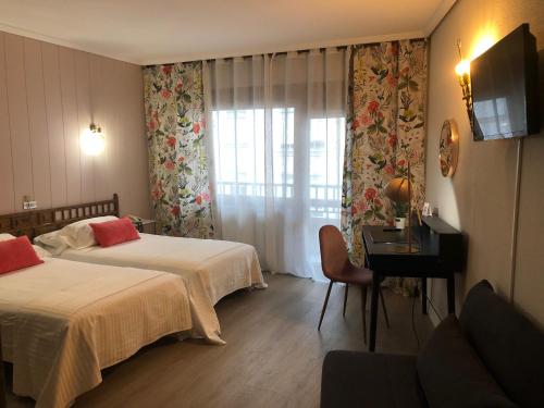 a hotel room with two beds and a television at Hotel Marqués de Santillana in Torrelavega