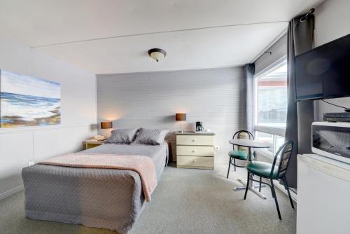 um quarto com uma cama, uma secretária e uma televisão em Motel Express em Saint-Antonin