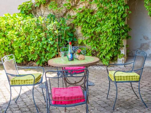 a table with three chairs and a bottle on it at Cottage du Château classé du tourisme 2 étoiles in Bouresse
