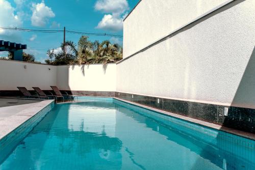 una piscina con sillas junto a una pared blanca en Hplus Premium Palmas en Palmas