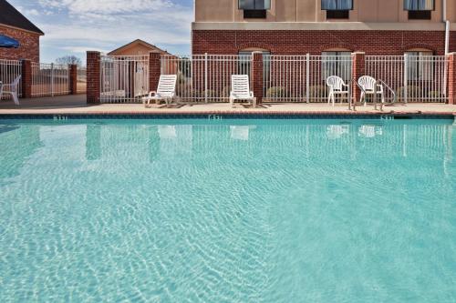 una piscina con sillas y un edificio en Holiday Inn Express Hotel & Suites Forest, an IHG Hotel, en Forest