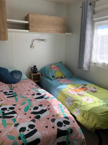 - une chambre avec 2 lits avec des pandas sur les draps dans l'établissement Mobile Home - Les Dunes de Contis, à Saint-Julien-en-Born