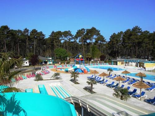 une grande piscine avec des chaises et un parc aquatique dans l'établissement Mobile Home - Les Dunes de Contis, à Saint-Julien-en-Born