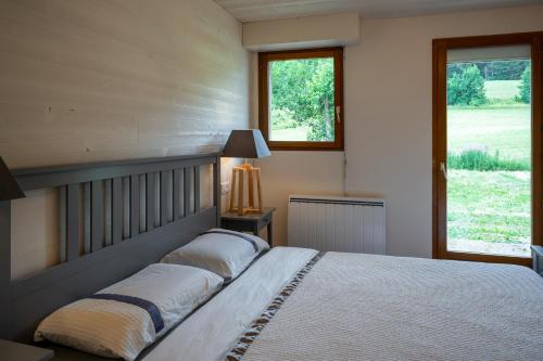 a bedroom with a large bed and two windows at Le Refuge in Lamoura