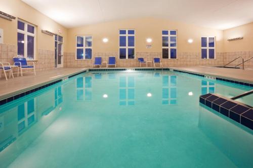 a swimming pool with blue chairs in a building at Holiday Inn Express Hotel & Suites Antigo, an IHG Hotel in Antigo