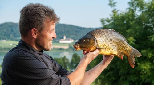 a man holding a fish in his hands at Hotel Seehof in Sankt Georgen am Längsee