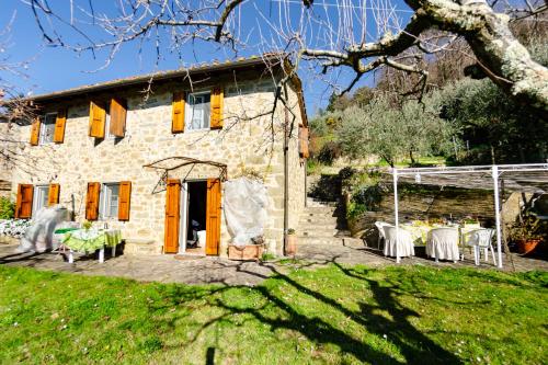 a stone house with tables and chairs in front of it at La Casa del Sole in Petrognano