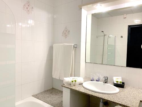 a white bathroom with a sink and a mirror at Hotel Restaurant Llansola in Sant Carles de la Ràpita