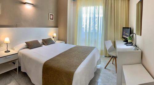 a hotel room with a large bed and a desk at Hotel Restaurant Llansola in Sant Carles de la Ràpita