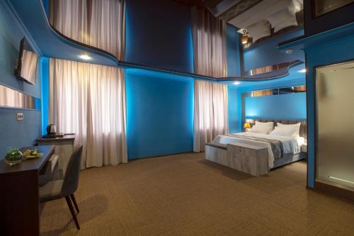 a bedroom with blue walls and a bed and a table at Georgia Gold in Gori